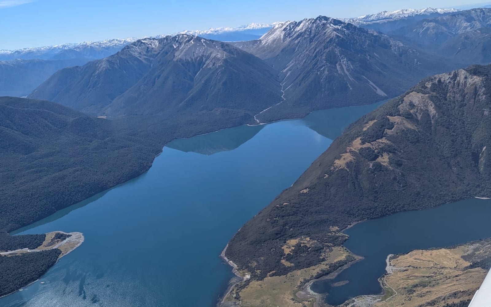 View across a mountain lake and surrounding ranges from a light aircraft in flight.